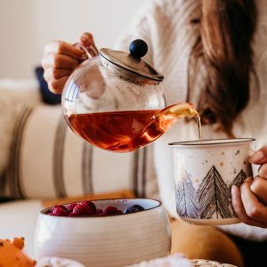 woman having a cup of tea at home during breakfast. Cute golden retriever dog besides. Healthy breakfast with fruits and sweets. lifestyle indoors