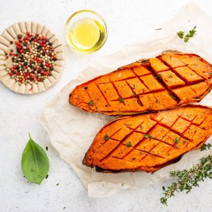 Two halves of baked yam sweet potato with spices and herbs, top view